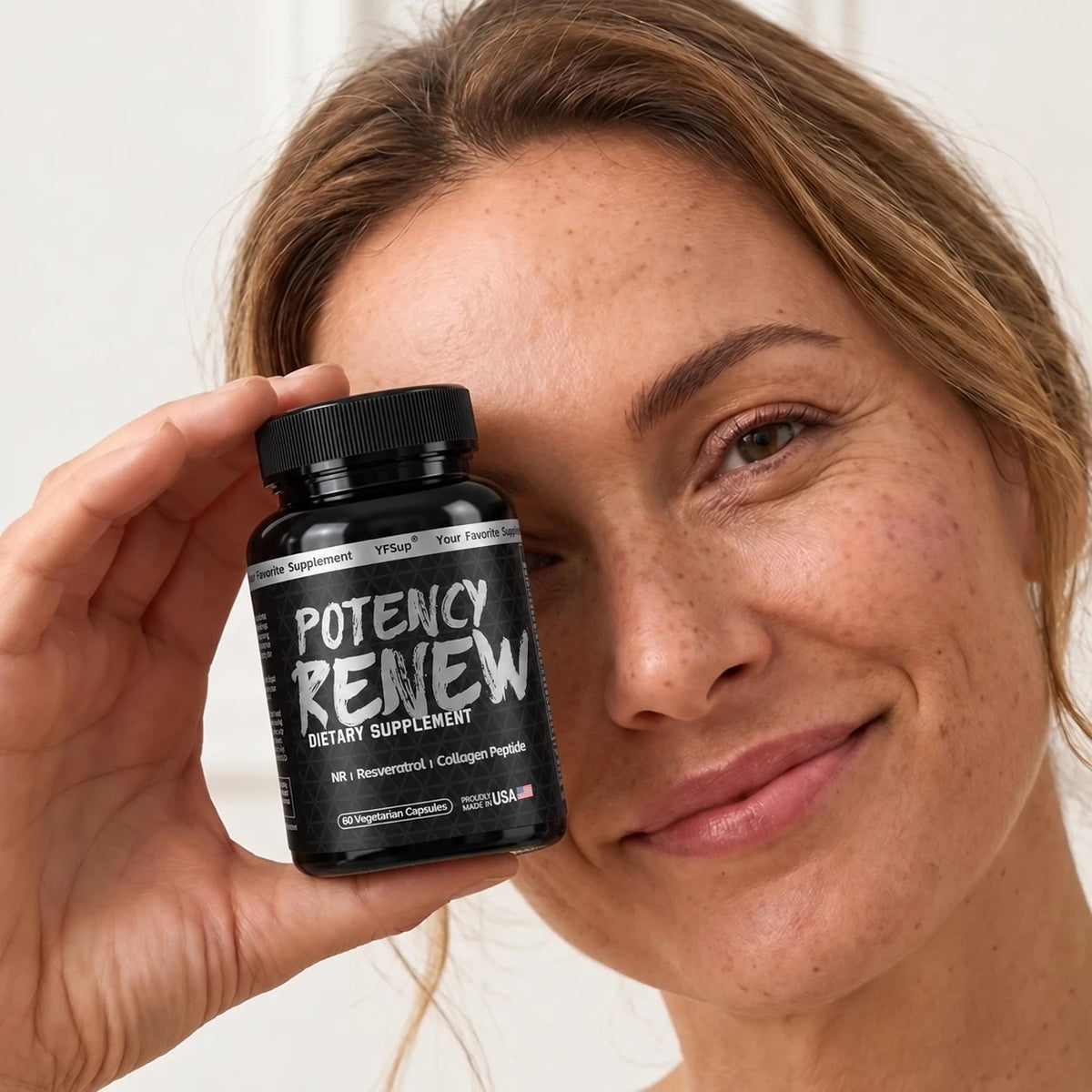 A smiling woman with freckles holding a bottle of Potency Renew beside her face
